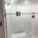 open area with glass shower panel instead of door.